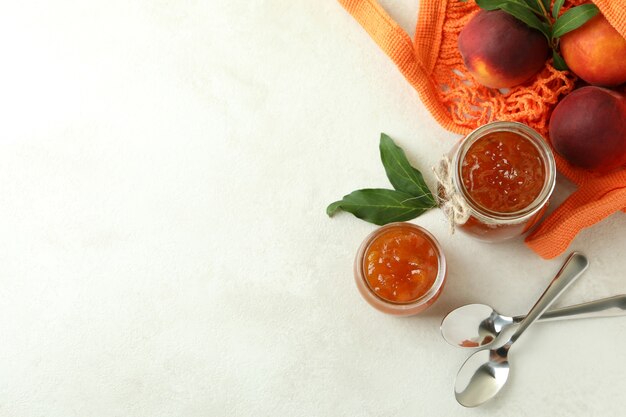 Mermelada de melocotón e ingredientes en la mesa con textura blanca