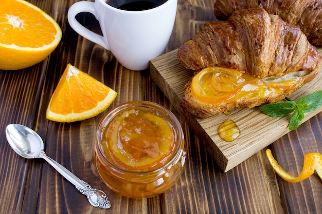 Mermelada de naranja casera en el tarro de cristal, croissants y café