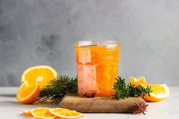 Mermelada de naranja en un frasco de vidrio con especias de invierno y ramas de abeto.