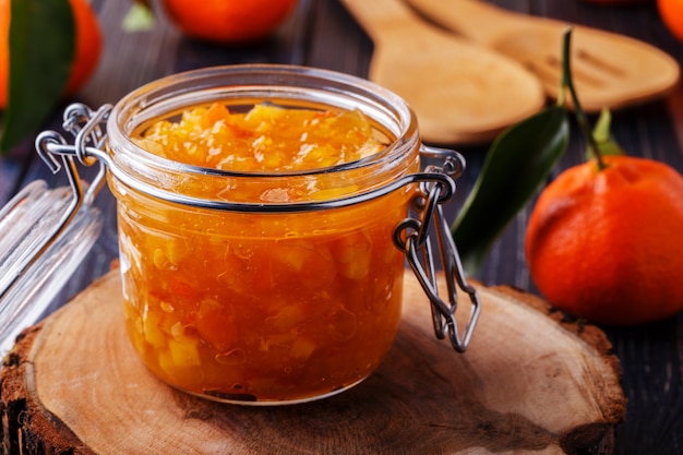 Mermelada de naranja en un frasco de vidrio sobre la mesa.