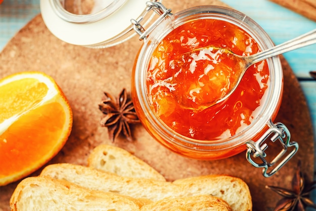 Mermelada de naranja en tarro de cristal con tostadas.