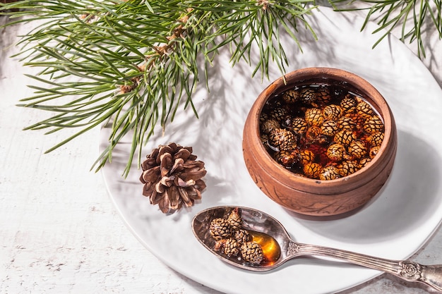 Mermelada de piña dulce. Postre tradicional siberiano, ramas frescas de hoja perenne. Luz dura de moda, sombra oscura. Fondo de madera blanca, espacio de copia