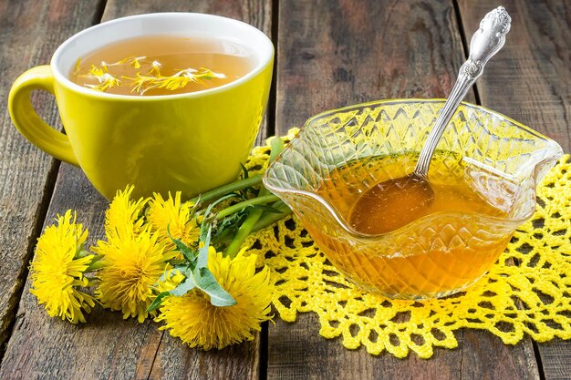 Mermelada primaveral de dientes de león, té de flores en una taza amarilla y un diente de león de flores en una servilleta de punto amarilla. enfoque selectivo