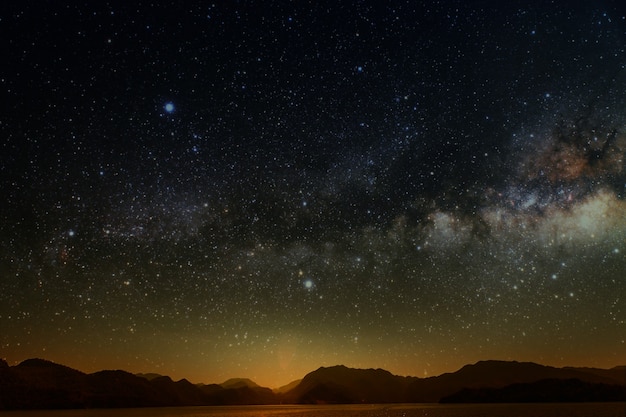 Mes en un cielo estrellado de fondo reflejado en el mar.