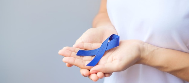 Mês de conscientização do câncer colorretal de março, mulher segurando fita azul escura para apoiar pessoas que vivem e estão doentes. Cuidados de saúde, esperança e conceito de dia mundial do câncer