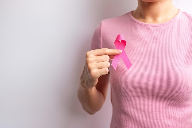 Mês de conscientização do câncer de mama de outubro rosa mão de mulher segura fita rosa e usa camisa para apoiar a vida e a doença das pessoas Mês nacional dos sobreviventes do câncer Conceito do dia da mãe e do dia mundial do câncer