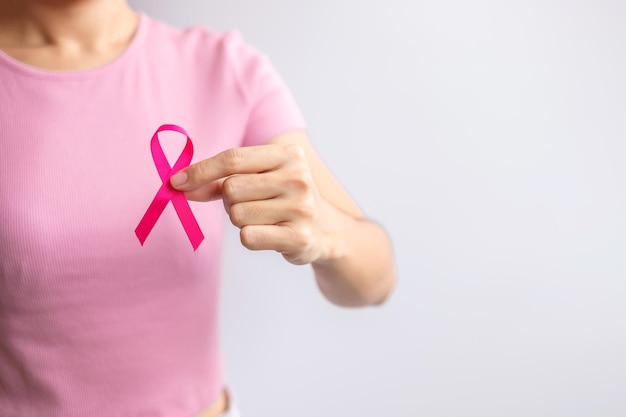 Mês de conscientização do câncer de mama de outubro rosa mão de mulher segura fita rosa e usa camisa para apoiar a vida e a doença das pessoas Mês nacional dos sobreviventes do câncer Conceito do dia da mãe e do dia mundial do câncer