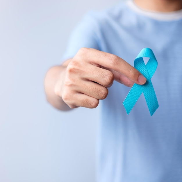 Mês de conscientização do câncer de próstata de novembro azul homem de camisa azul com a mão segurando a fita azul para apoiar a vida e a doença das pessoas saúde homens internacionais pai diabetes e dia mundial do câncer