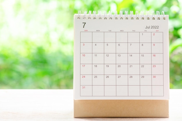 Mês de julho, mesa de calendário 2022 para o organizador de planejamento e lembrete na mesa de madeira com fundo verde da natureza.