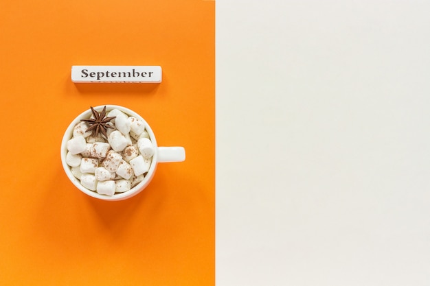 Mês do calendário de madeira setembro e xícara de chocolate com marshmallows em fundo laranja bege