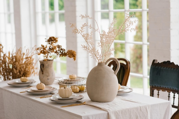 Mesa de acción de gracias con calabazas y flores secas decoraciones de otoño en un comedor moderno de estilo vintage