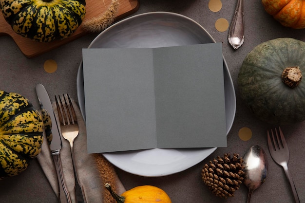 Mesa de acción de gracias de otoño con tarjeta de invitación de menú en blanco rodeada de calabazas festivas