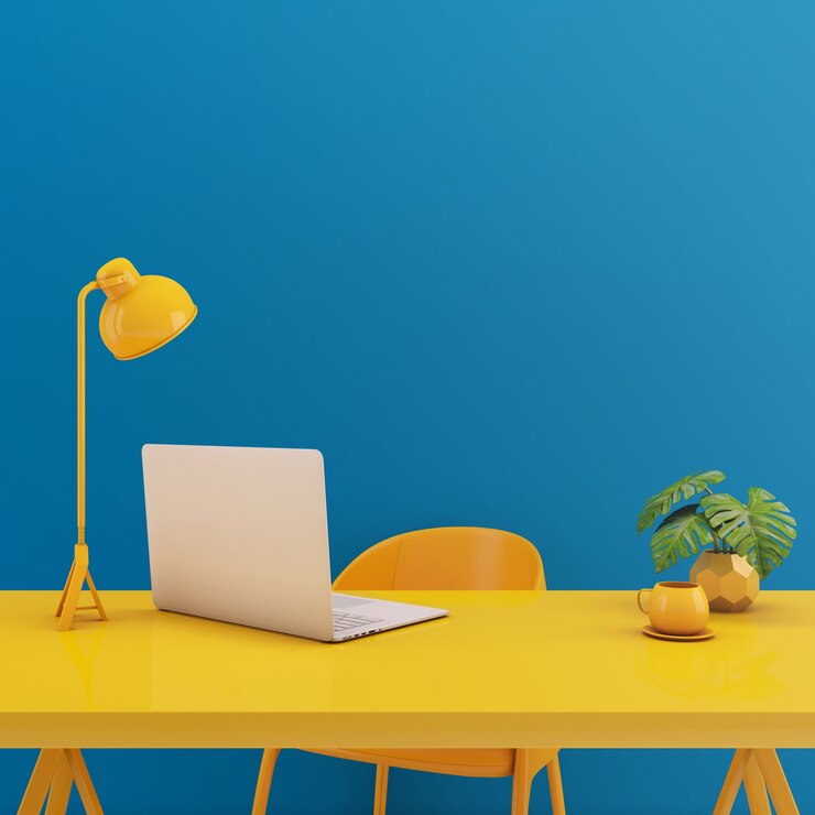 Mesa amarilla con portátil sobre fondo azul.