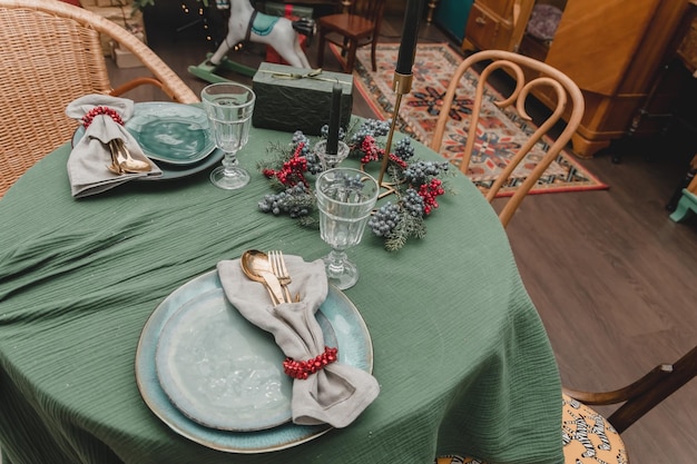 Mesa de Año Nuevo ambientando la Navidad al estilo de los años 50 del año nuevo apartamento rústico decorado en estilo antiguo sin comida con platos, velas y árboles de Navidad