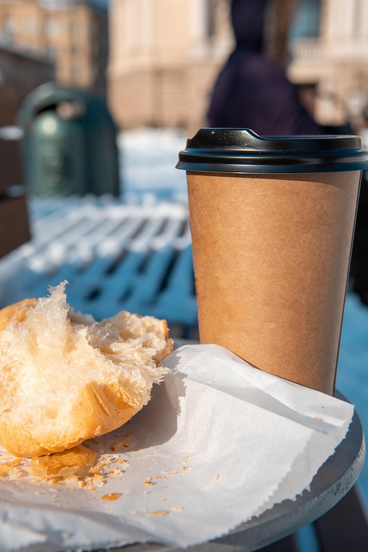 Foto mesa ao ar livre com banco de café para viagem e croissant close-up