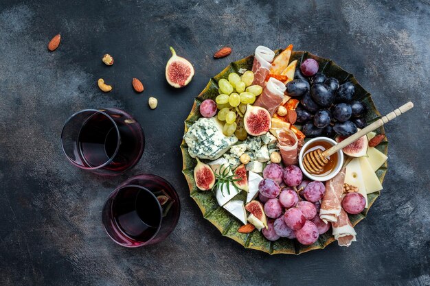 Mesa de aperitivos con bocadillos antipasti italianos y vino en copas queso jamón nueces palitos de pan de frutas Delicioso concepto de comida equilibrada Vista superior de formato de banner largo