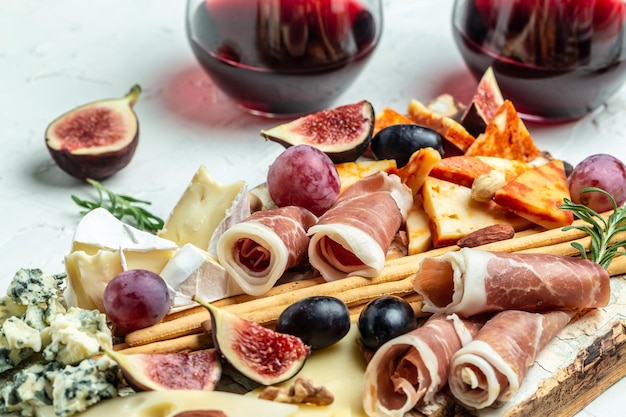 Mesa de aperitivos con bocadillos antipasti italianos y vino en vasos queso jamón nueces palitos de pan de frutas Delicioso concepto de comida equilibrada