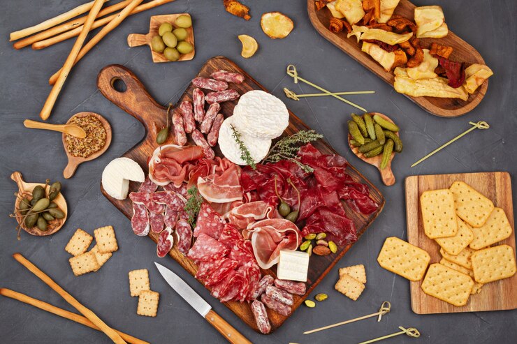 Mesa de aperitivos con diferentes antipasti, charcutería, snacks y vino