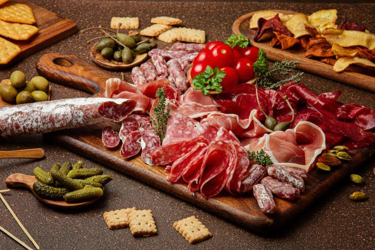 Mesa de aperitivos con diferentes antipasti, queso, embutidos, snacks y vino. Salchicha, jamón, tapas, aceitunas, queso y galletas para fiesta buffet.