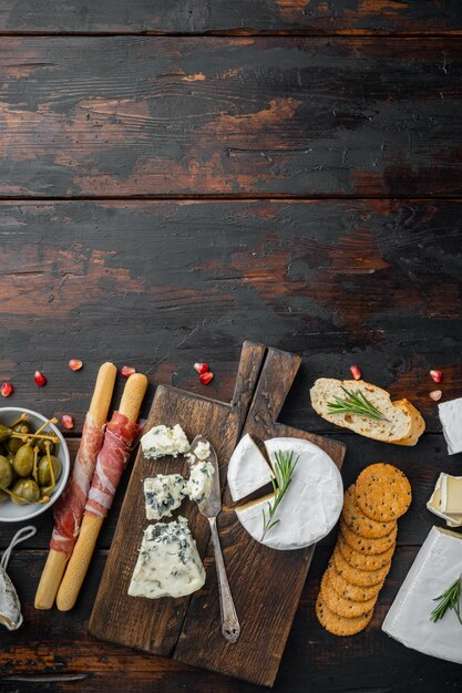 Mesa de aperitivos con diferentes antipasti, sobre fondo de madera oscura, vista superior con espacio para copiar texto