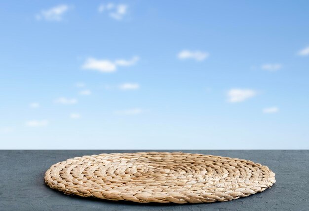 Mesa azul de madera con servilleta y espacio libre para instalar un producto o diseño sobre un fondo de cielo azul con nubes