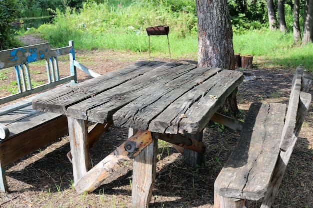 Mesa y bancos caseros de tablas muy antiguas, estacionamiento turístico en la orilla del río, verano