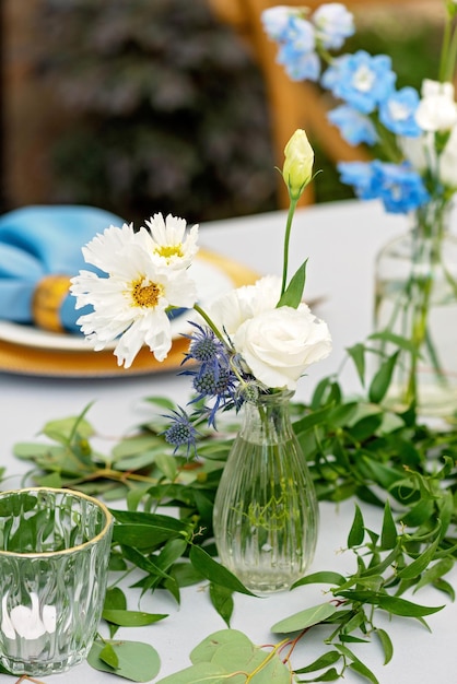 Mesa de banquete de boda con servilletas azules, cubiertos de oro, cristal, flores frescas y velas. Decoraciones de boda. Enfoque selectivo suave.