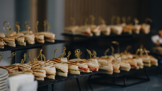 Mesa de banquete de catering bellamente decorada con diferentes bocadillos y aperitivos con sándwich