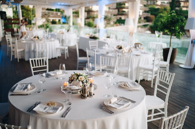 Mesa de banquete redonda de recepción de mesa de cena de boda con mantel blanco y sillas chiavari blancas