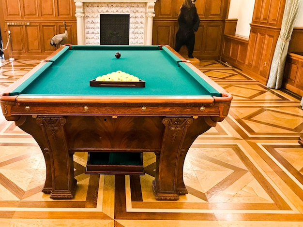 Mesa de billar grande y cara de madera con un paño verde para jugar al billar