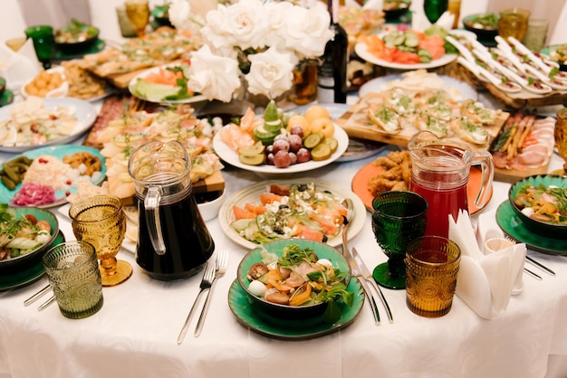 La mesa blanca redonda está llena de una gran cantidad de comida y varios refrigerios en un interior lujoso, una hermosa porción de la mesa festiva.