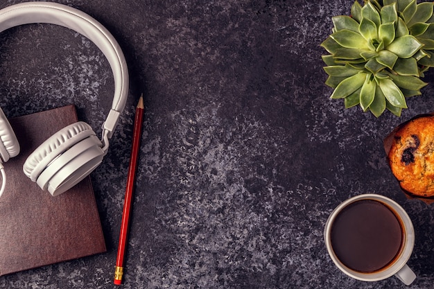 Mesa con bloc de notas, auriculares y café.