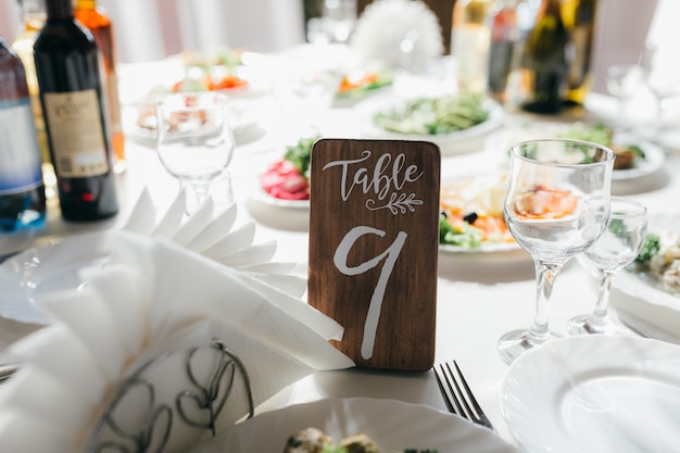 Foto mesa de boda decorada y numerada con comida, bebida, electrodomésticos y flores.