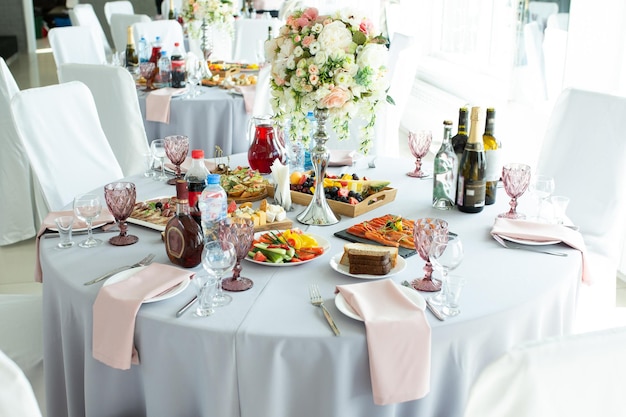Una mesa de boda para invitados decorada con flores y un mantel estilo diseñador con comida y bebida Decoración y diseño de catering para eventos