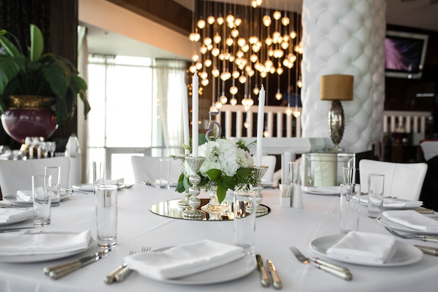La mesa para bodas está decorada con flores frescas y velas blancas. Boda floristería. Ramo de rosas