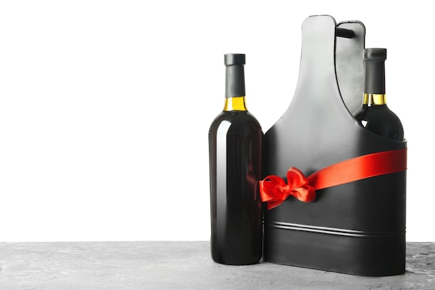 Mesa con botellas de vino y caja de regalo sobre fondo blanco.