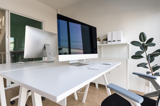 Mesa branca e cadeira com monitor de computador e armário de arquivo moderno em escritório doméstico branco