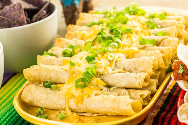 Mesa buffet de fiesta con taquitos de pollo y otra comida tradicional mexicana.