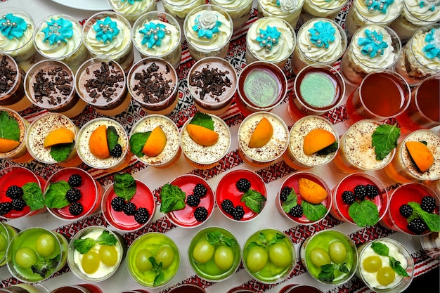 Mesa de buffet de primer plano con gelatina de frutas frescas y crema. Buffet de bodas con postres.