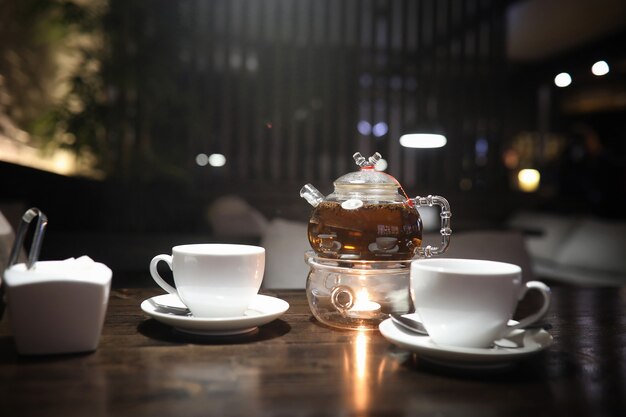 Una mesa en un café con un cóctel y una taza de té.