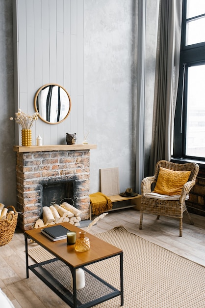 Una mesa de café junto a la chimenea de una casa de campo y una silla de mimbre en el salón de la casa en estilo escandinavo.