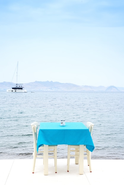 Mesa de café servida con un mantel azul cerca de la costa del mar para unas vacaciones relajadas