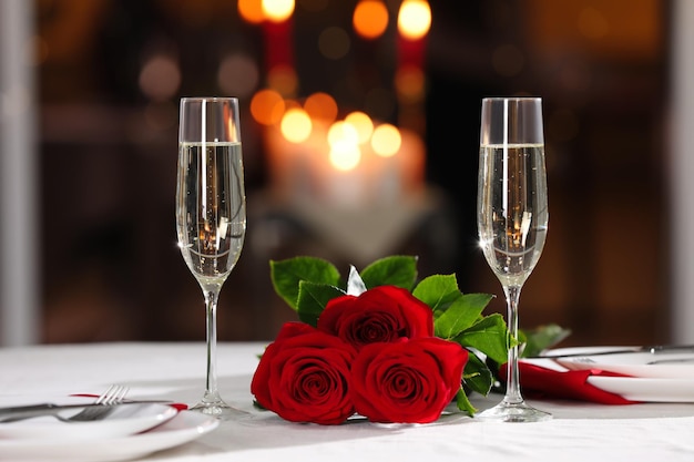 Mesa de cena romántica con copas de champán y rosas rojas en el restaurante