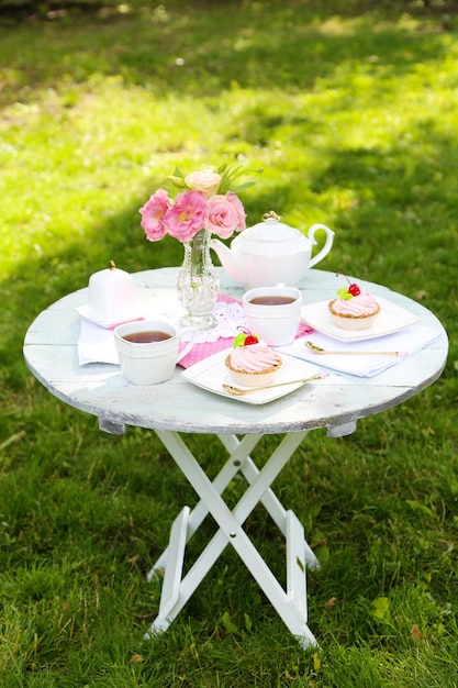 Mesa de centro con tazas de té y sabrosos pasteles en el jardín