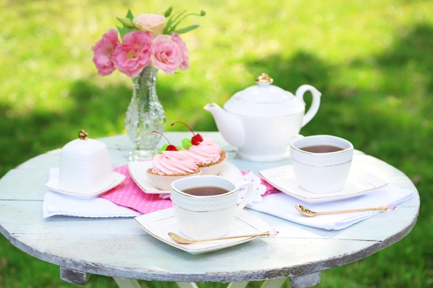 Mesa de centro con tazas de té y sabrosos pasteles en el jardín