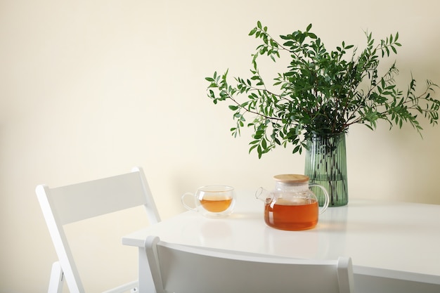 Mesa de cocina blanca con té y planta en habitación luminosa