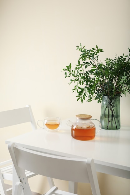 Mesa de cocina blanca con té y planta en habitación luminosa