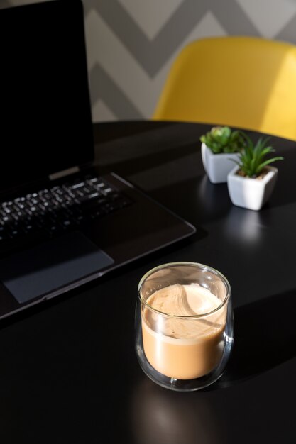 Foto mesa de cocina moderna negra con laptop, taza de café y plantas.