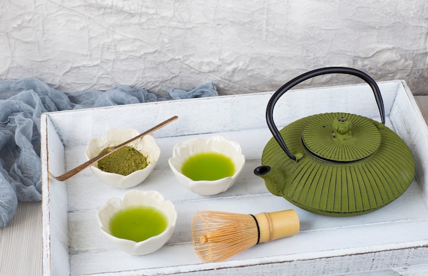 Foto en la mesa coincide con el té en los tazones para beber, batidor de té, cuchara, tetera - ceremonia del té