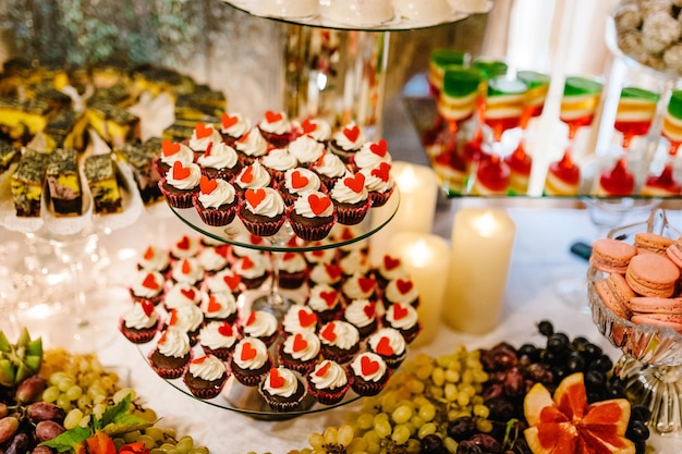 Mesa colorida con dulces y golosinas para la recepción de la fiesta de bodas, mesa de postres decorada. Deliciosos dulces en buffet de dulces. Mesa de postres para una fiesta. tortas, cupcakes.